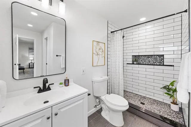 a bathroom with a sink a toilet a mirror and shower