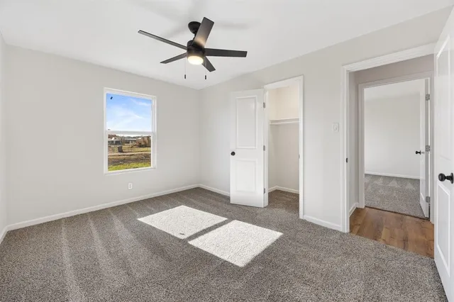 an empty room with ceiling fan and windows