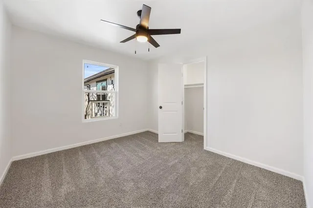 an empty room with window and ceiling fan