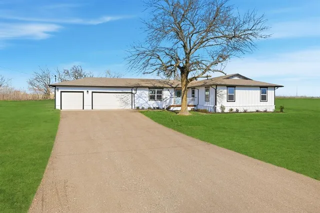 a front view of a house with a garden and trees