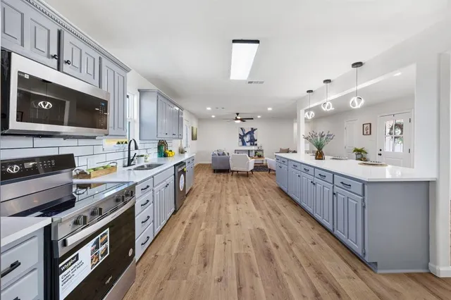 a large kitchen with stainless steel appliances kitchen island granite countertop a large counter top and a stove top oven