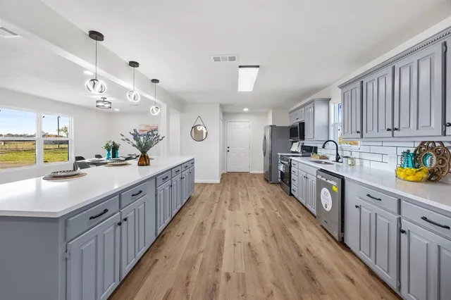 a kitchen with kitchen island granite countertop lots of counter top space and wooden floor