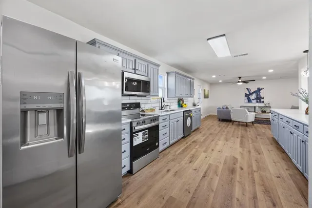 a large kitchen with kitchen island a large counter top space a sink stainless steel appliances and cabinets