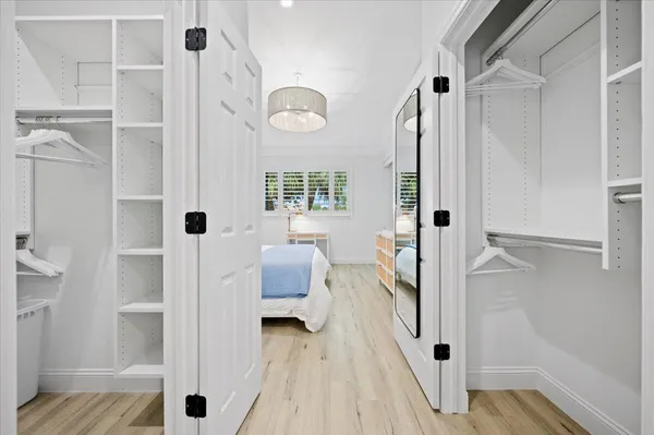 walk in closet with wooden floor and bathroom view