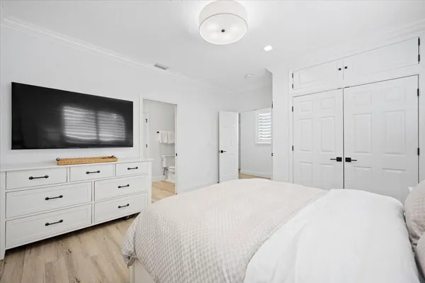 a bedroom with a bed and a flat screen tv in white walls
