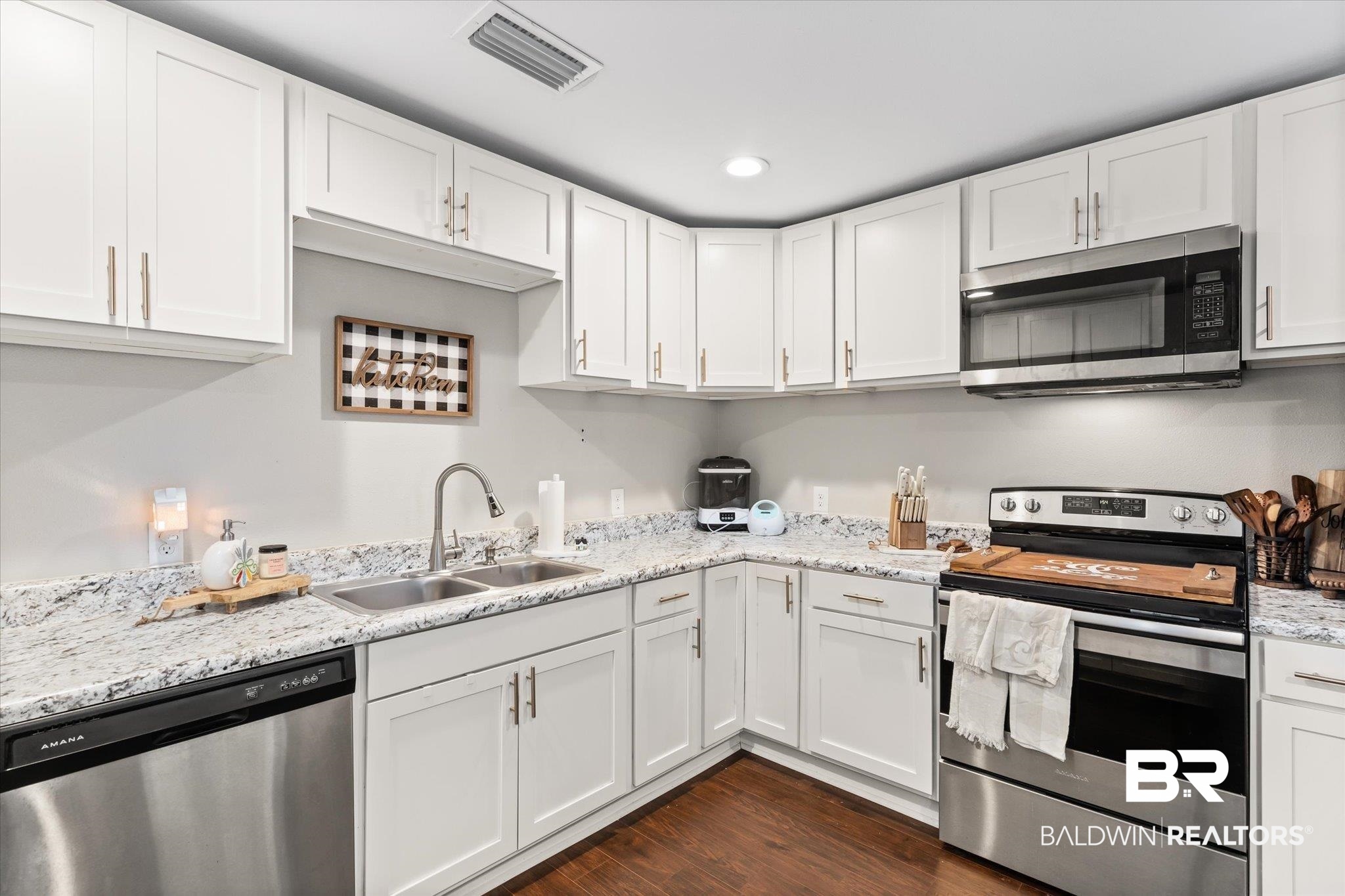419 Pierce Street Saraland, AL 36571 - Photo 7 of 21 Kitchen with sink, light stone counters, dark hardwood / wood-style floors, stainless steel appliances, and white cabinets