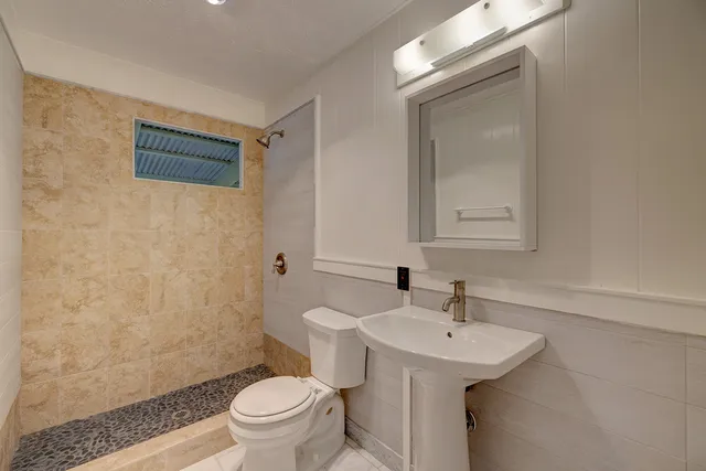 a bathroom with a sink a toilet and shower
