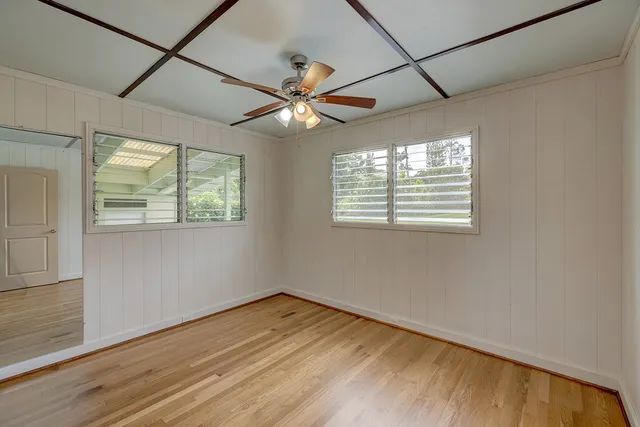 a view of empty room with wooden floor and fan