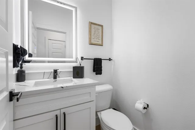 a bathroom with a sink mirror vanity and toilet