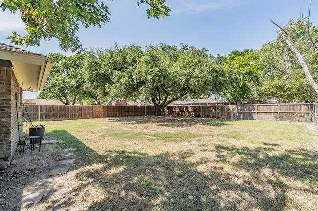 a view of a backyard with plants and a bench