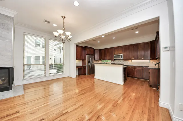 a view of an empty room with wooden floor and a fireplace