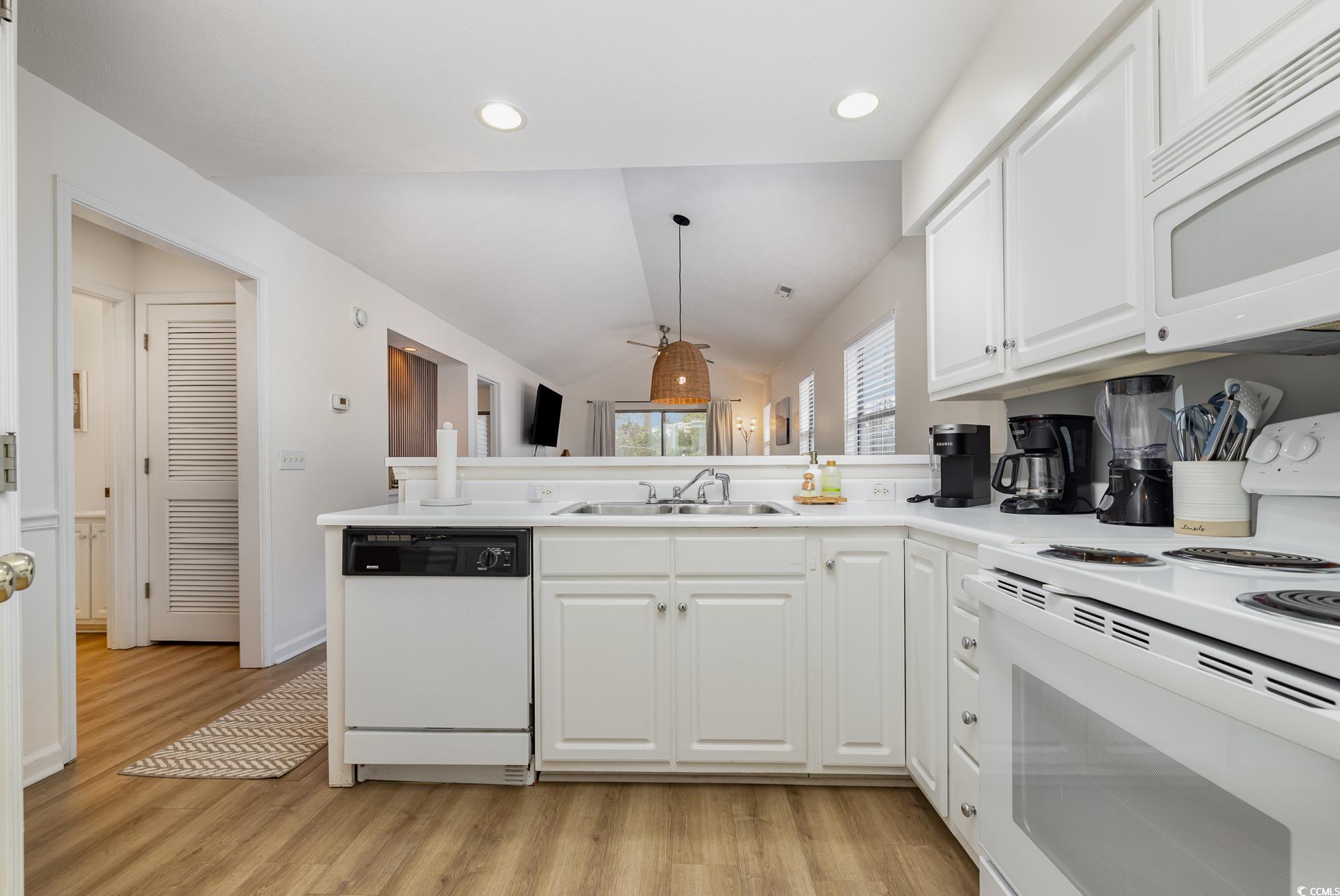 504 Pinehurst Lane, Unit 18H Pawleys Island, SC 29585 - Photo 11 of 28 Kitchen with white appliances, white cabinets, lofted ceiling, a peninsula, and light wood-type flooring