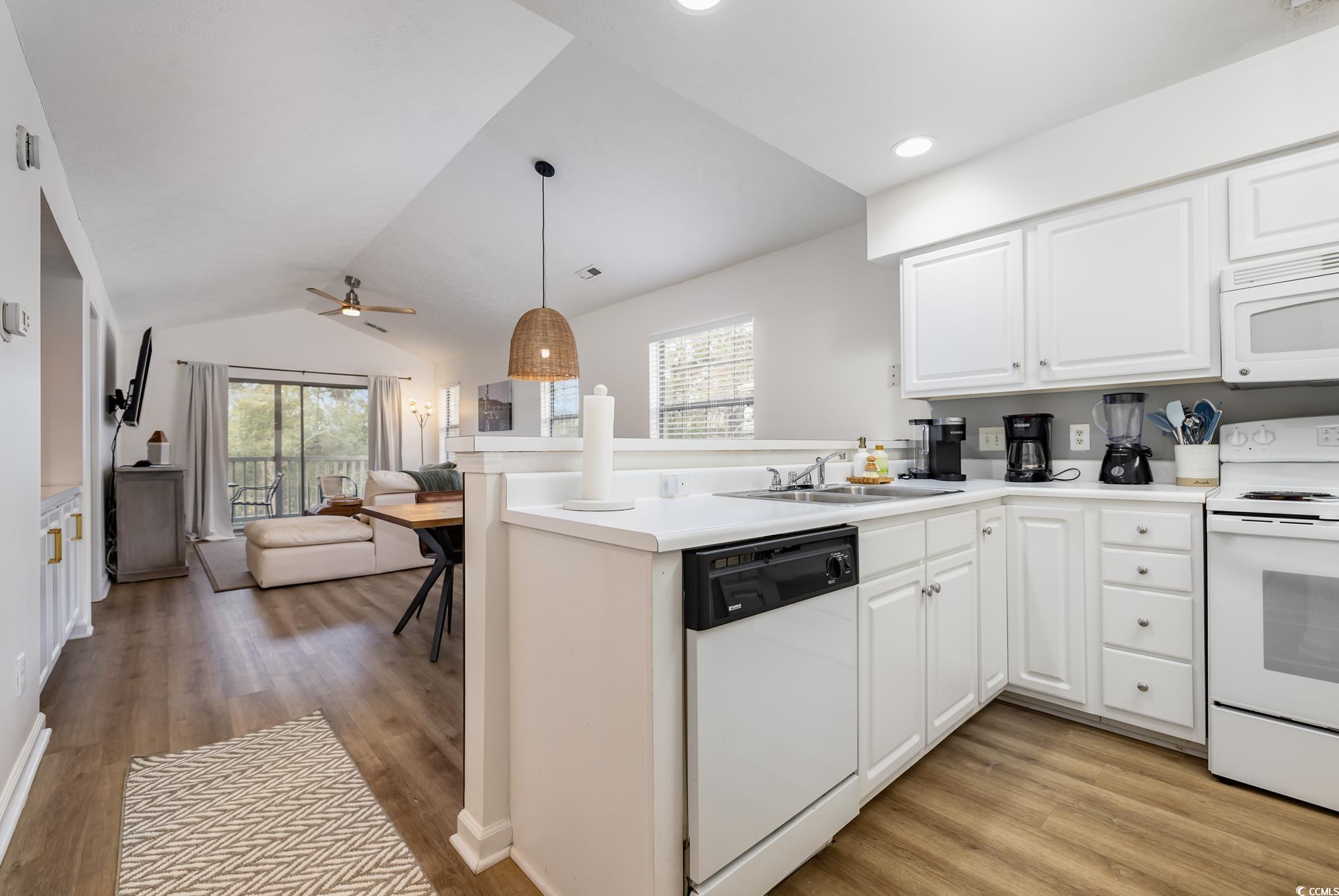 504 Pinehurst Lane, Unit 18H Pawleys Island, SC 29585 - Photo 8 of 28 Kitchen with a peninsula, white cabinets, white appliances, lofted ceiling, and light wood-style floors