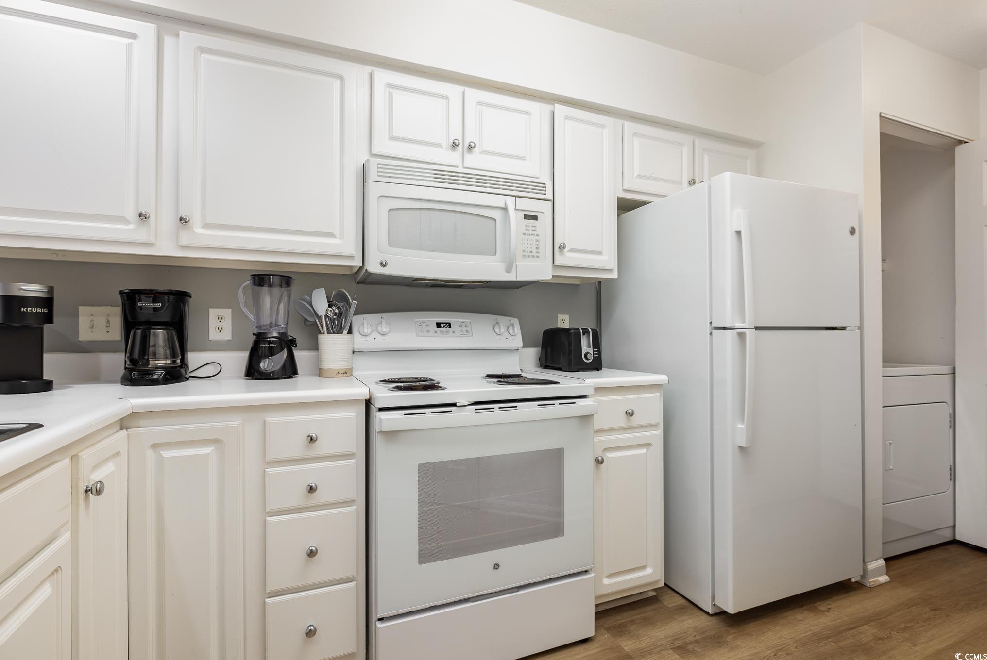 504 Pinehurst Lane, Unit 18H Pawleys Island, SC 29585 - Photo 9 of 28 Kitchen featuring white appliances, white cabinets, washer / clothes dryer, light countertops, and light wood-style flooring