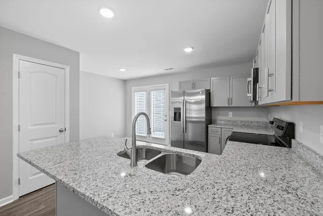 a kitchen with granite countertop a sink a stove and cabinets