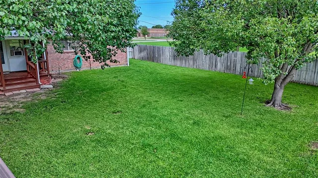 a view of a backyard with large trees and wooden fence