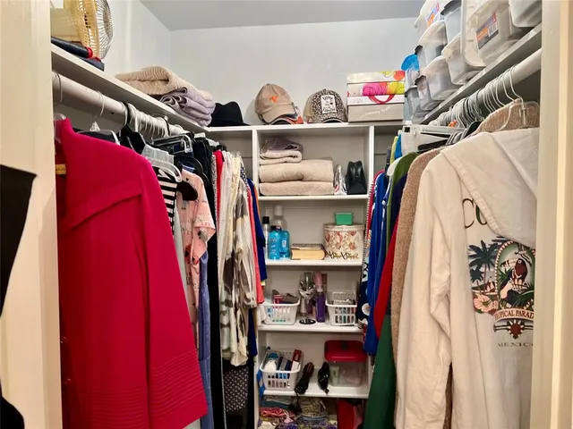 a view of walk in closet with clothes and shoes