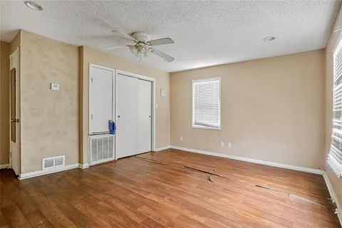 a view of an empty room with wooden floor and a window