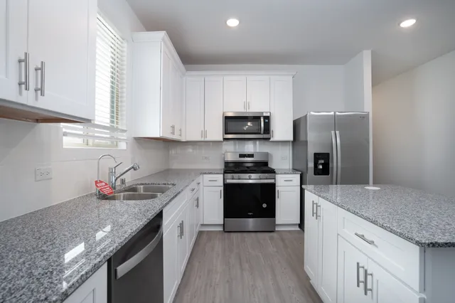 a kitchen with stainless steel appliances granite countertop a sink dishwasher a refrigerator and a stove