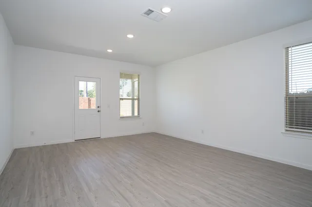 an empty room with wooden floor and windows