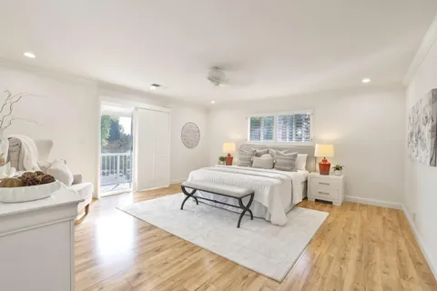 a spacious bedroom with a bed and wooden floor