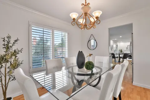 a view of a dining room with furniture a chandelier and wooden floor