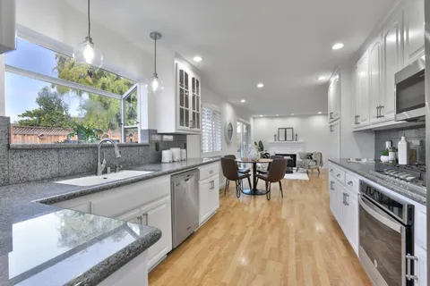 a kitchen with stainless steel appliances granite countertop sink stove top oven and cabinets