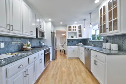 a large kitchen with stainless steel appliances granite countertop a lot of counter space and wooden floors