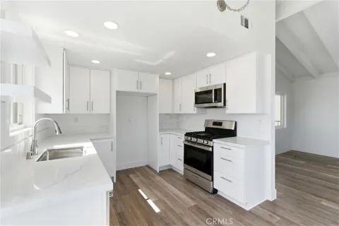 a kitchen with a sink stainless steel appliances and white cabinets