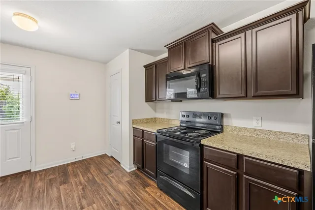a kitchen with granite countertop wooden cabinets stainless steel appliances and a window