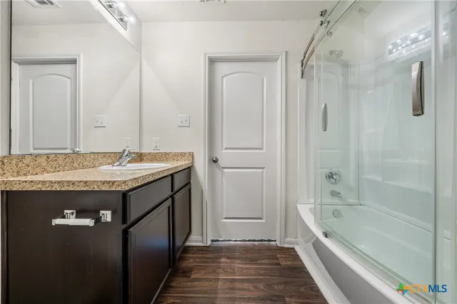 a bathroom with a granite countertop sink a mirror and a bathtub
