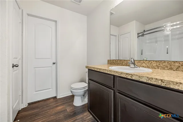 a bathroom with a granite countertop sink toilet and a mirror
