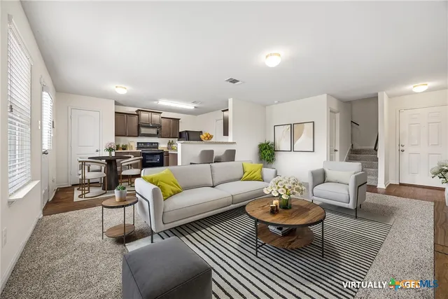 a living room with furniture a rug kitchen view and a table