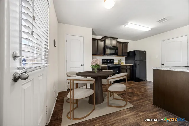 a kitchen with stainless steel appliances a dining table chairs and a refrigerator