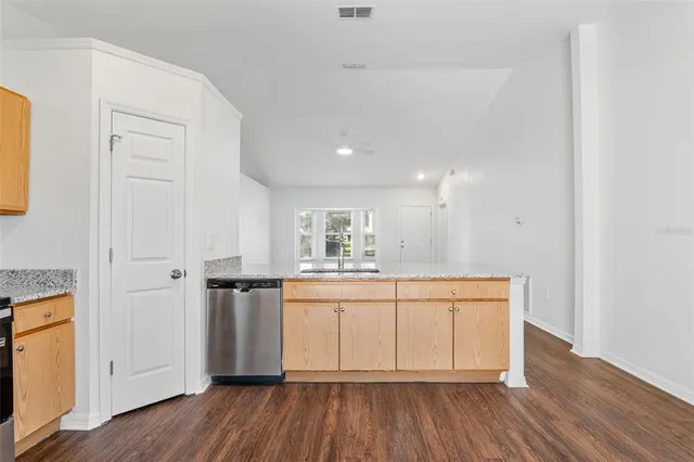 a kitchen with stainless steel appliances granite countertop a white cabinets and wooden floor