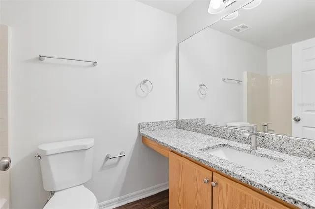 a bathroom with a granite countertop sink a toilet and a mirror