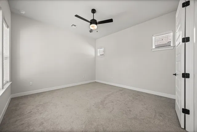 an empty room with a ceiling fan and window