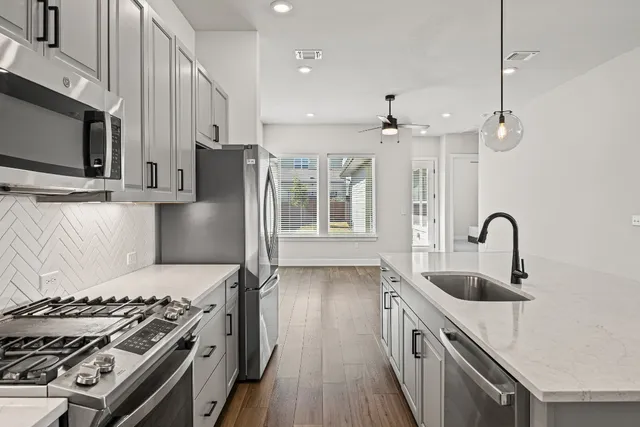 a kitchen with stainless steel appliances granite countertop a sink stove and refrigerator