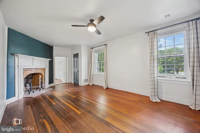 a view of empty room with wooden floor and fireplace