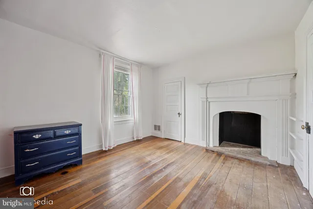a view of empty room with wooden floor and fireplace