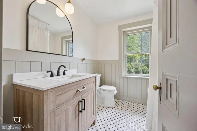 a bathroom with a sink a toilet a mirror and a window