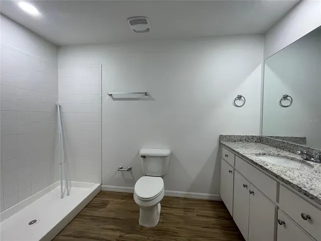 a bathroom with a granite countertop sink a toilet and shower