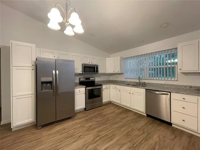 a large kitchen with cabinets wooden floor and stainless steel appliances