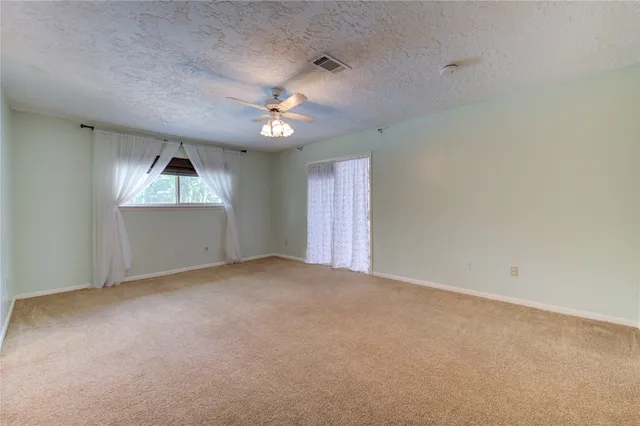 an empty room with windows and ceiling fan