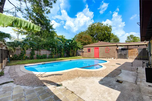 a view of backyard with swimming pool and seating space