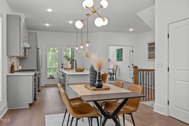 a kitchen with a dining table chairs stainless steel appliances and cabinets