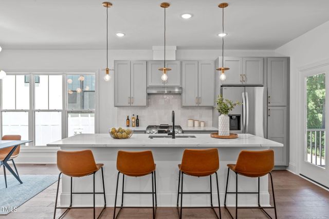 a kitchen with stainless steel appliances kitchen island granite countertop a dining table chairs and white cabinets