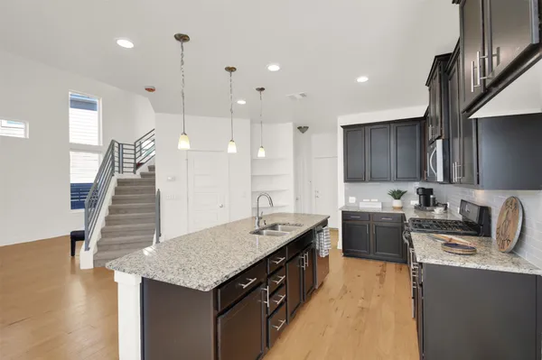 a kitchen with granite countertop kitchen island stainless steel appliances a sink a stove top oven a counter space and cabinets