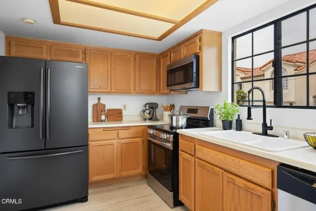 a kitchen with a sink a refrigerator and a stove top oven with wooden floor