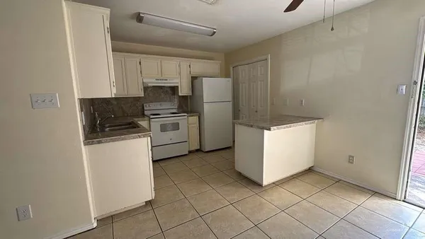 a kitchen with a refrigerator a stove top oven and cabinets